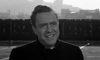 Movie still from “Birdman of Alcatraz” (1962), directed by John Frankenheimer – Black and white photograph of a man smiling for the camera; Close Up shot, Over the shoulder angle