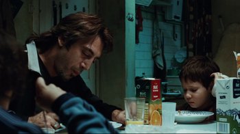 Movie still from “Biutiful” (2010), directed by Alejandro G. Iñárritu – A man sitting at a dining table with a child; Medium shot, Over the shoulder angle