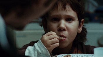 Movie still from “Biutiful” (2010), directed by Alejandro G. Iñárritu – A young boy is eating a piece of food; Close Up shot, Over the shoulder angle