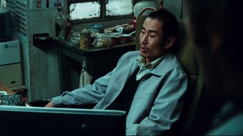 Movie still from “Biutiful” (2010), directed by Alejandro G. Iñárritu – A man sitting in a chair in front of an open laptop computer; Medium shot, High angle