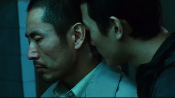 Movie still from “Biutiful” (2010), directed by Alejandro G. Iñárritu – A man with his head down next to another man with his head down; Close Up shot, Over the shoulder angle