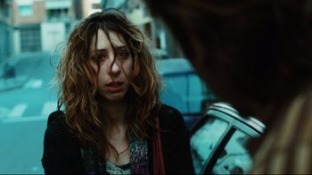 Movie still from “Biutiful” (2010), directed by Alejandro G. Iñárritu – A woman with long curly hair standing on the street; Close Up shot, Over the shoulder angle