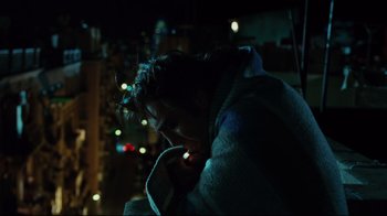 Movie still from “Biutiful” (2010), directed by Alejandro G. Iñárritu – A woman wrapped in a blanket looking at her cell phone; Medium shot, Overhead angle