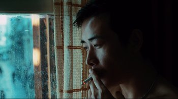 Movie still from “Biutiful” (2010), directed by Alejandro G. Iñárritu – A man smoking a cigarette in front of a window; Close Up shot, Low angle