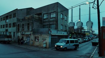 Movie still from “Biutiful” (2010), directed by Alejandro G. Iñárritu – A van driving down a street near a building; Extreme Wide shot, Low angle