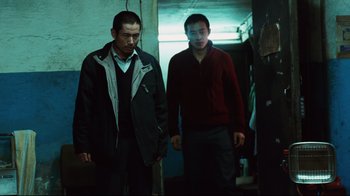 Movie still from “Biutiful” (2010), directed by Alejandro G. Iñárritu – Two men are standing in a dark room; Medium shot, Low angle