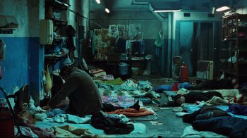 Movie still from “Biutiful” (2010), directed by Alejandro G. Iñárritu – A group of people sitting on the ground in a room; Wide shot, High angle