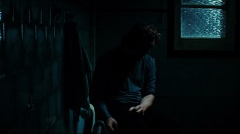Movie still from “Biutiful” (2010), directed by Alejandro G. Iñárritu – A man sitting on a chair in a dark room; Medium shot, Over the shoulder angle