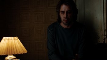 Movie still from “Biutiful” (2010), directed by Alejandro G. Iñárritu – A man sitting in front of a lamp in a dark room; Medium shot, Low angle