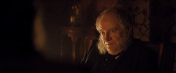 An old man with a long white beard sitting in a chair