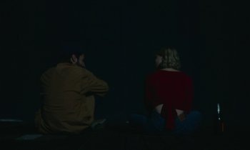 Movie still from “Black Bear” (2020), directed by Lawrence Michael Levine – A man and a woman sitting on the ground at night; Medium shot, High angle