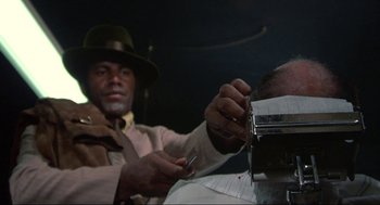 Movie still from “Black Caesar” (1973), directed by Larry Cohen – A man cutting another man's hair with scissors; Close Up shot, Low angle