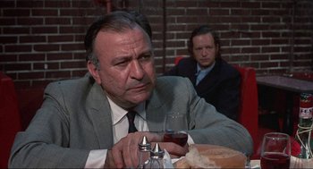 Movie still from “Black Caesar” (1973), directed by Larry Cohen – An older man sitting at a table with a glass of red wine; Close Up shot, Over the shoulder angle