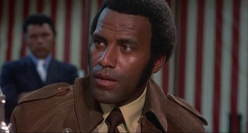 Movie still from “Black Caesar” (1973), directed by Larry Cohen – A person wearing a suit and tie; Close Up shot, Low angle