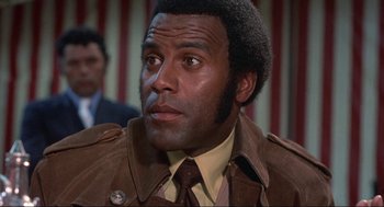 Movie still from “Black Caesar” (1973), directed by Larry Cohen – A man in a brown jacket and a brown tie; Close Up shot, Low angle