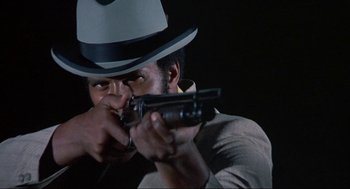 Movie still from “Black Caesar” (1973), directed by Larry Cohen – A man wearing a hat and holding a gun; Close Up shot, Low angle