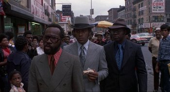 Movie still from “Black Caesar” (1973), directed by Larry Cohen – A group of men walking down a street; Medium shot, Low angle