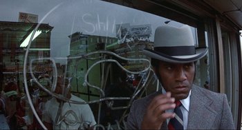 Movie still from “Black Caesar” (1973), directed by Larry Cohen – A man wearing a hat is looking out of a window; Close Up shot, Low angle