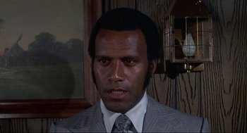 Movie still from “Black Caesar” (1973), directed by Larry Cohen – A person wearing a suit and tie; Close Up shot, Low angle