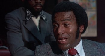 Movie still from “Black Caesar” (1973), directed by Larry Cohen – A man in a suit and a red tie; Close Up shot, Low angle
