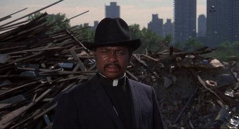 Movie still from “Black Caesar” (1973), directed by Larry Cohen – A man wearing a black hat and a black suit; Close Up shot, Low angle