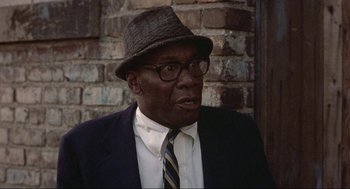 Movie still from “Black Caesar” (1973), directed by Larry Cohen – An older man wearing a suit and a hat; Close Up shot, Low angle