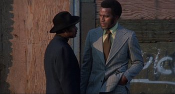 Movie still from “Black Caesar” (1973), directed by Larry Cohen – Two men standing next to each other wearing suits and hats; Medium shot, Low angle