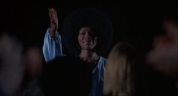 Movie still from “Black Caesar” (1973), directed by Larry Cohen – A black woman with a black hat is raising her hand; Medium shot, Low angle
