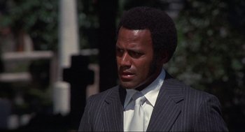 Movie still from “Black Caesar” (1973), directed by Larry Cohen – A man in a suit and tie looking to his left; Close Up shot, Low angle