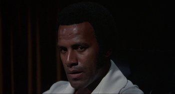 Movie still from “Black Caesar” (1973), directed by Larry Cohen – A person wearing a white shirt; Close Up shot, Low angle