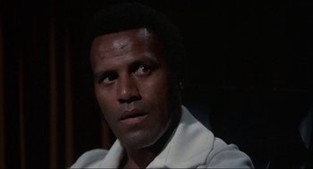 Movie still from “Black Caesar” (1973), directed by Larry Cohen – A person wearing a white shirt; Close Up shot, Low angle