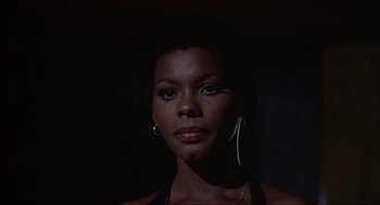 Movie still from “Black Caesar” (1973), directed by Larry Cohen – A black woman with short black hair wearing a black top; Close Up shot, Low angle