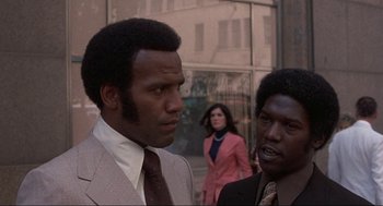 Movie still from “Black Caesar” (1973), directed by Larry Cohen – A man and a woman standing next to each other on the street; Close Up shot, Low angle