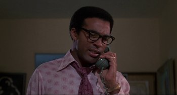 Movie still from “Black Caesar” (1973), directed by Larry Cohen – A man talking on a phone while wearing a tie; Close Up shot, Low angle