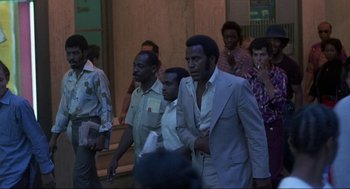 Movie still from “Black Caesar” (1973), directed by Larry Cohen – A group of men walking down a street; Medium shot, High angle
