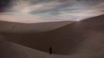 Movie still from “Black Is King” (2020), directed by Julian Klincewicz – A person standing on top of a sand dune; Extreme Wide shot, High angle