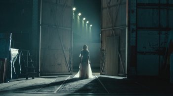 Movie still from “Black Is King” (2020), directed by Julian Klincewicz – A woman in a white dress standing in front of a door way; Wide shot, Low angle
