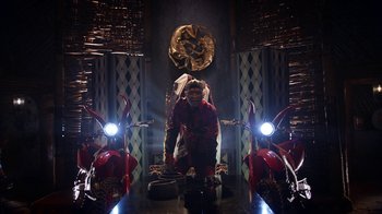 Movie still from “Black Is King” (2020), directed by Julian Klincewicz – A man standing next to two motorcycles in a dark room; Wide shot, Low angle