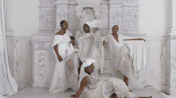 Movie still from “Black Is King” (2020), directed by Julian Klincewicz – A group of women dressed in white posing for a picture; Extreme Wide shot, Low angle