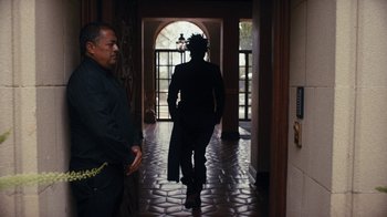 Movie still from “Black Is King” (2020), directed by Julian Klincewicz – Two men are walking in the hallway of a house; Medium shot, Over the shoulder angle