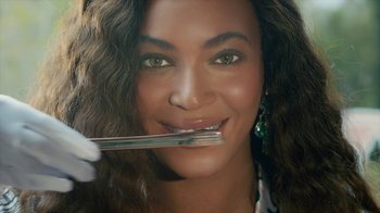 Movie still from “Black Is King” (2020), directed by Julian Klincewicz – A person holding a fork in her mouth; Extreme Close Up shot, Overhead angle