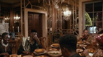 Movie still from “Black Is King” (2020), directed by Julian Klincewicz – Two people sitting at a table eating food; Medium shot, Over the shoulder angle