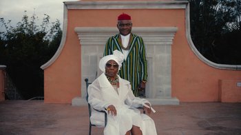 Movie still from “Black Is King” (2020), directed by Julian Klincewicz – An older woman sitting in front of an older man; Medium shot, Low angle