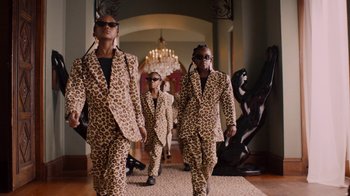 Movie still from “Black Is King” (2020), directed by Julian Klincewicz – A group of people in animal print suits walking down a hall way; Wide shot, Low angle