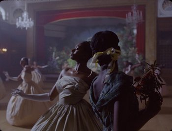 Movie still from “Black Is King” (2020), directed by Julian Klincewicz – A couple of women standing next to each other in a room; Medium shot, Over the shoulder angle