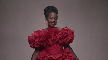 Movie still from “Black Is King” (2020), directed by Julian Klincewicz – A woman in a red dress posing for a picture; Medium shot, Low angle
