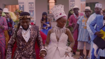 Movie still from “Black Is King” (2020), directed by Julian Klincewicz – A man and a woman holding hands while wearing a dress; Medium shot, Low angle