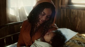 Movie still from “Black Is King” (2020), directed by Julian Klincewicz – A woman holding a child in her arms; Close Up shot, Over the shoulder angle