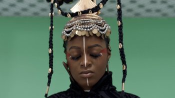 Movie still from “Black Is King” (2020), directed by Julian Klincewicz – A woman with a black and gold headdress on her head; Close Up shot, Overhead angle