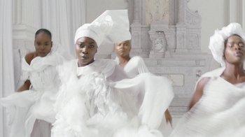 Movie still from “Black Is King” (2020), directed by Julian Klincewicz – A woman in a white dress and a man in a white hat; Medium shot, Low angle